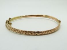 A 9ct rose gold bangle with engraved ivy decoration, 5.4g
