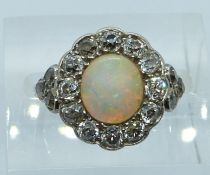 An 18ct white gold ring set with an oval opal cabochon surrounded by old cut diamonds, 3.6g, size