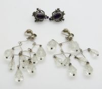 A pair of silver earrings set with amethysts and a pair of crystal chandelier earrings
