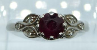 A platinum ring set with a round cut ruby of approximately 0.8ct and diamonds, 4.4g, size R
