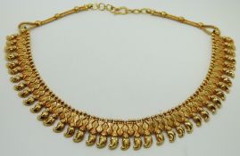 Indian yellow metal fringe necklace of stylised floral and foilate design links below ball
