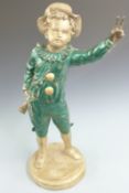 A late 19th/20thC painted metal figure of a young musician with mandolin giving a two fingered