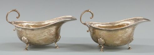 Pair of George V hallmarked silver sauce boats with gadrooned edge and raised on three feet,