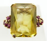 A yellow metal ring marked 14k set with a mixed emerald cut synthetic yellow sapphire and