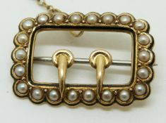 A Victorian brooch set with seed pearl and enamel in the form of a buckle