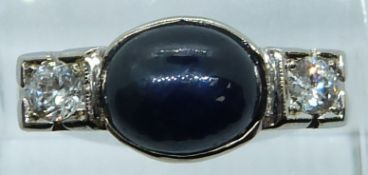 A 14k white gold ring set with a sapphire cabochon of approximately 2.1ct and two diamonds each