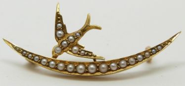 Edwardian yellow metal brooch in the form of a crescent and swallow set with seed pearls, 3.5cm