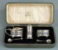 George V cased three piece hallmarked silver cruet set with blue glass liners, Birmingham 1920 maker