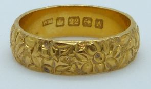 A 22ct gold wedding band with relief moulded flower decoration, Birmingham 1925, maker WM, 9g,