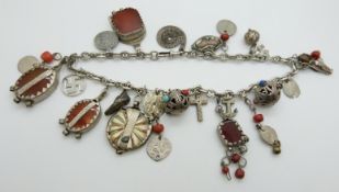 A large silver necklace set with various charms including a cross, agate, coins, Fumsup charm etc