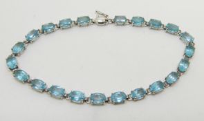 A 9ct white gold tennis bracelet set with oval blue topaz, 5.9g