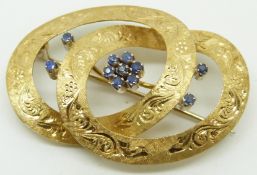 An 18ct gold brooch in a knot design with engraved decoration and set with sapphires, 4.3 x 3cm,