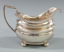 Georgian hallmarked silver cream or milk jug with gadrooned edge, raised on four squat ball feet,