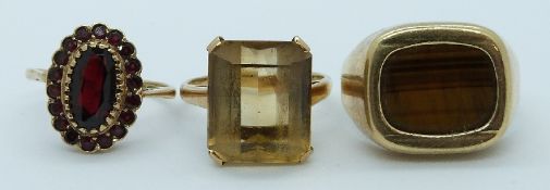 Three 9ct gold rings, one set with tiger's eye, set with a citrine and another set with garnets,