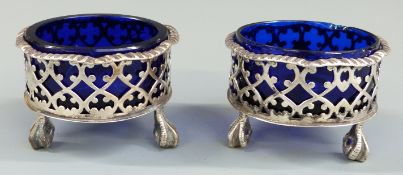 Pair of Victorian hallmarked silver salts with pierced bodies and blue glass liners, raised on