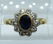 An 18ct gold ring set with an oval cut sapphire surrounded by diamonds, 4.3g, size N