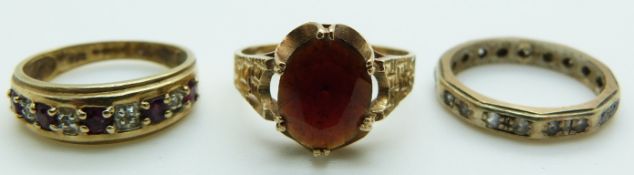 A 9ct gold eternity ring, a 9ct gold ring set with an oval garnet and a 9ct gold ring set with