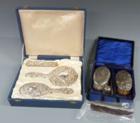 Cased hallmarked silver mounted dressing table set comprising hand mirror, two brushes and a comb,