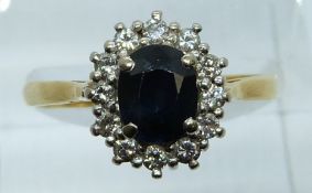 An 18ct gold ring set with an oval cut sapphire surrounded by diamonds, 3.9g, size Q