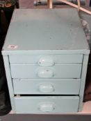 A painted metal four drawer desk top chest