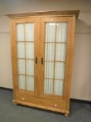 An antique pine double door glazed cabinet fitted with a drawer,