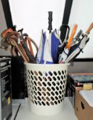 A large plastic tub containing a quantity of assorted walking sticks and umbrellas