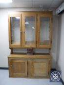 A pine triple door glazed kitchen dresser fitted with cupboards beneath