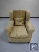 An early twentieth century wing backed chair upholstered in floral fabric