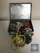 A mid 20th century tin of costume jewellery, beads,