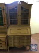 A blonde oak bureau bookcase with leaded glass doors