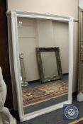 A white swept framed mirror,