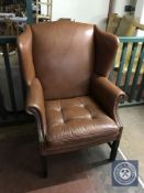 A twentieth century tan leather wing backed armchair