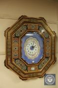 A highly ornate wall clock in a decorative frame with quartz movement, 63 cm x 73 cm.
