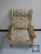 A blonde oak framed wing backed chair upholstered in floral fabric