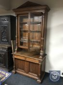 A 19th century oak glazed bookcase with pillar support fitted with cupboard doors