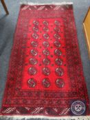 A fringed Afghan Bokhara rug on red ground,