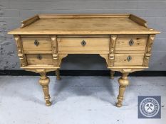 A 20th century pine desk fitted with five drawers on turned legs