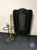 A 20th century hand painted fire screen together with a cast stick stand containing sticks,