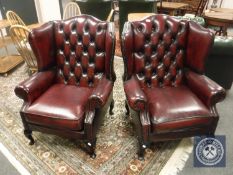 A pair of oxblood buttoned leather Chesterfield style wing backed armchairs, width each 84 cm.