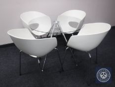 A circular glass topped metal pedestal dining table and four chairs
