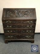 A George III heavily carved oak fall fronted bureau,