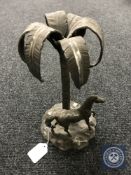 A cast metal figure of a horse standing by a palm tree