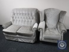 A two seater buttoned back settee upholstered in fabric together with similar wingback chair