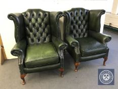 A pair of green leather Chesterfield style wing armchairs,