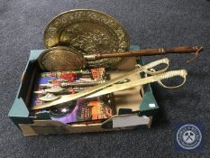 A box of brass embossed wall plaque, bed warming pan, pair of brass cutlasses,