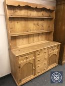 A pine kitchen dresser fitted with cupboards and drawers beneath,