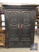 An Oriental style carved and ebonised double door cabinet