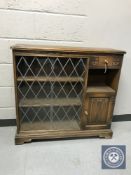 A Priory oak sliding glass door bookcase fitted with a cupboard and drawer