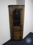 A reproduction oak leaded glass door corner cabinet