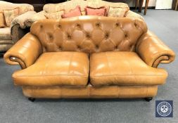 A buttoned tan leather scroll arm two seater settee